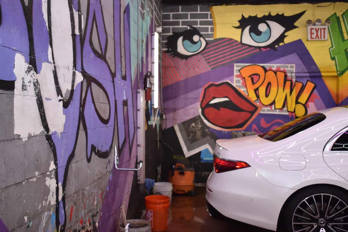 White sedan parked against a hand-painted pop-art wall