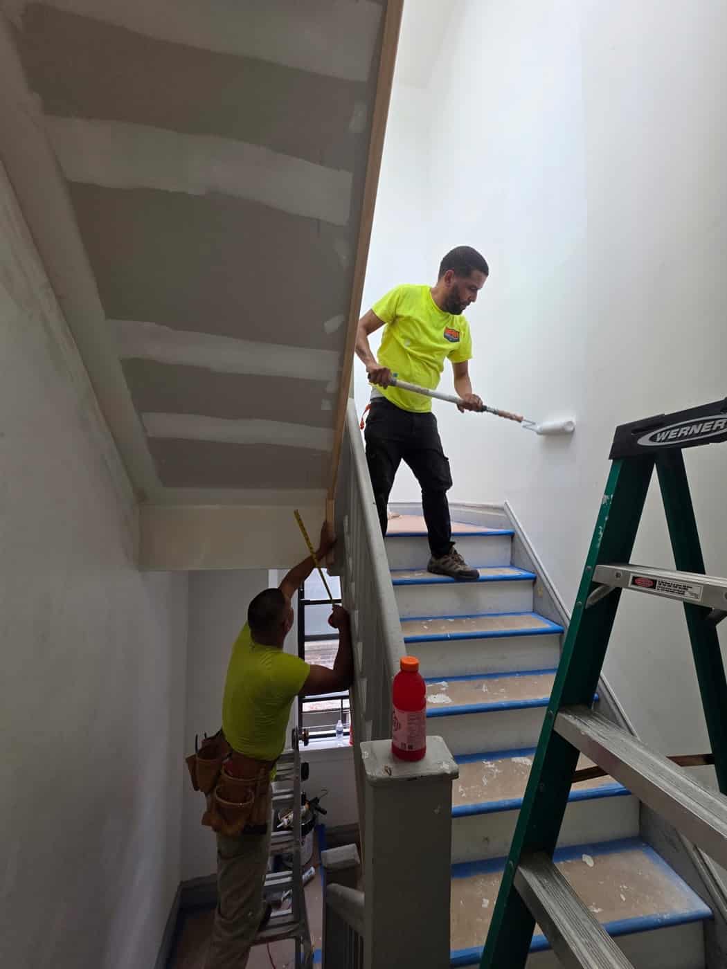 Painter on a ladder cutting in a stairwell ceiling