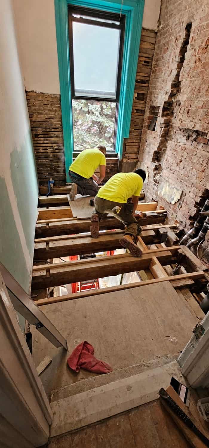 Gut renovation in progress with exposed joists and brick