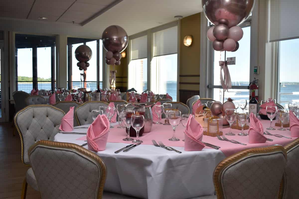 Waterfront event room styled with balloons and set tables
