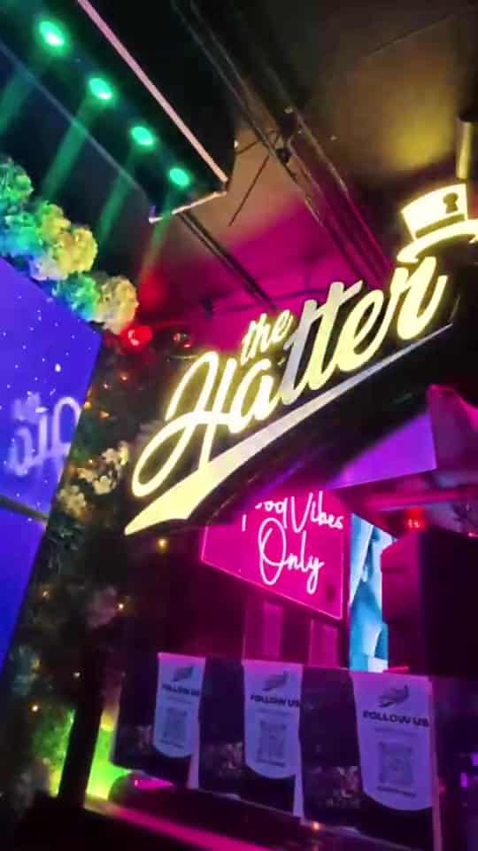 Neon Hatter sign glowing above a bar entrance